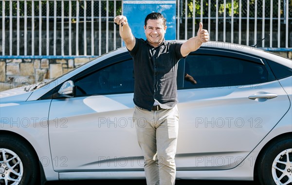 Driver leaning on the car showing the key