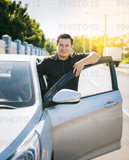 Happy driver leaning on the car door in the street