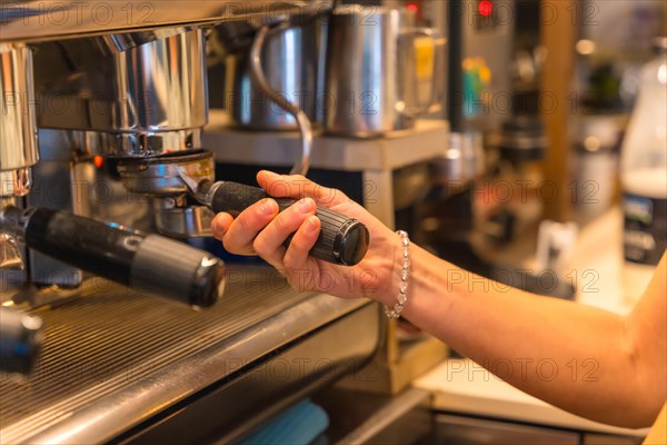 Hands of female coffee shop owner preparing coffee in a coffee machine