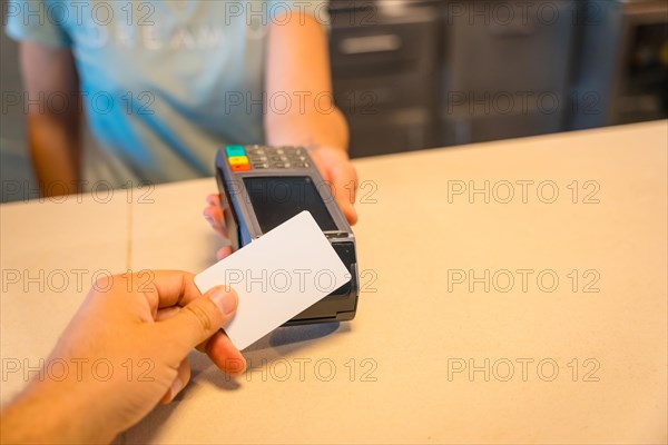 Unrecognizable waitress handing over the dataphone to collect with the contact with the client's credit card