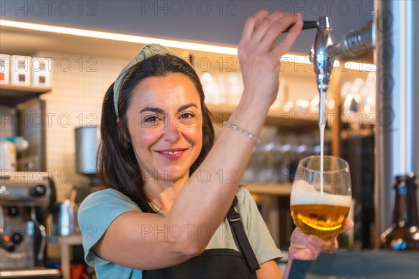 Smiling waitress brewing a blonde beer in a tap