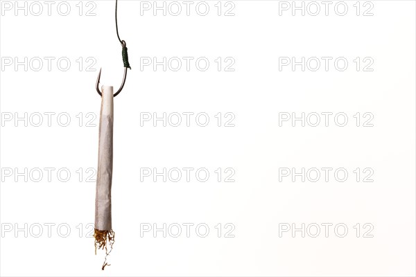 Marijuana cigarette hanging from a hook drug addiction concept close-up isolated on white background