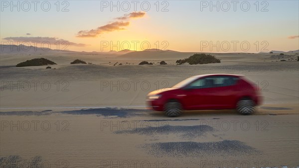 Red blurred car on sandy asphalt road