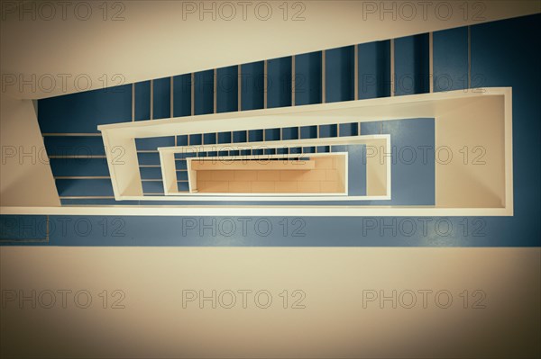 Staircase with white banister and blue vinyl floor from top to bottom