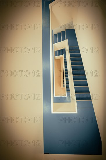 Staircase with white banister and blue vinyl floor from top to bottom