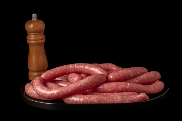 Homemade meat sausages with pepper shaker isolated on black background and copy space