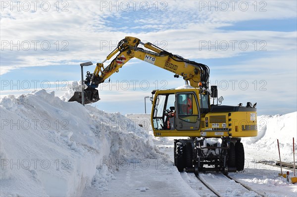 Two-way excavator clears the tracks of the Harz narrow-gauge railway from snow on the Brocken