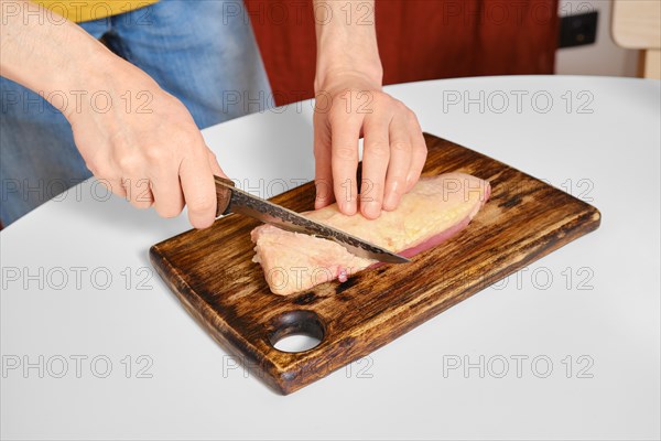 Unrecognizable man cuts the skin crosswise on a duck breast