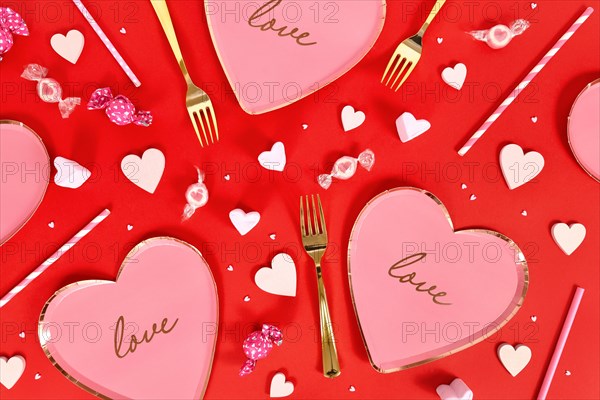 Valentine's Day party flat lay with heart shaped plates and candy on red background