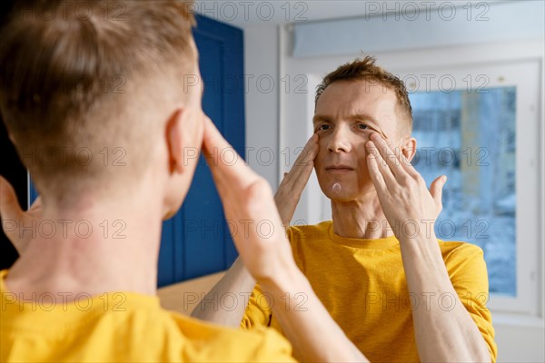 Mature adult man massaging face rubbing cream into skin