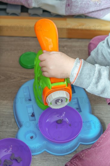 Unrecognizable child playing with a plasticine toy on the floor of his bedroom