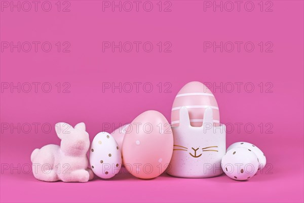 Pink and white painted easter eggs and cute easter egg cup in shape of bunny on pink background