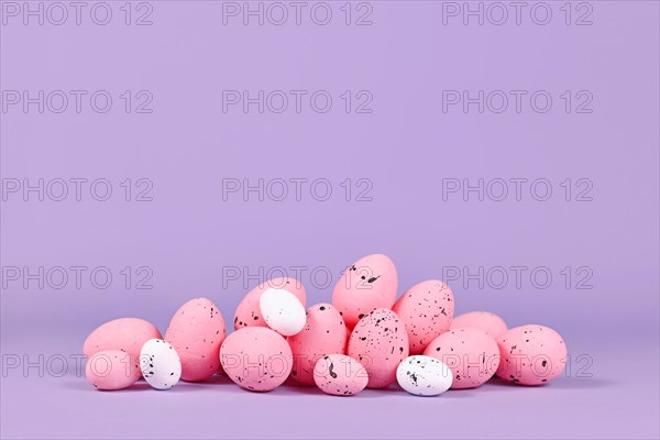 Pink Easter quail eggs on violet background with copy space