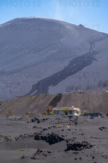 Damaged house in front of the new volcano Tajogaite at the visitor centre Canos de Fuego