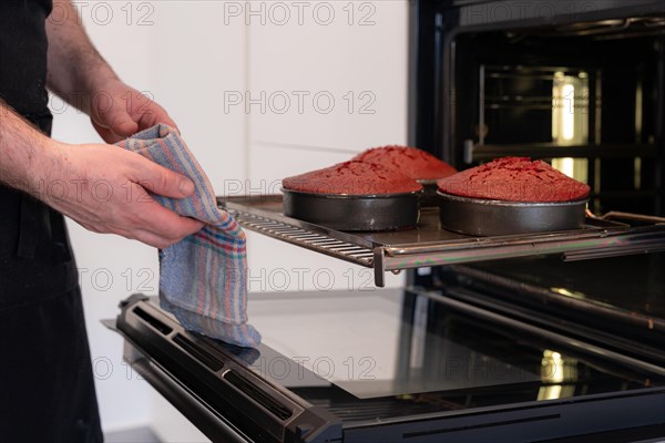 A man baker bakes a red velvet cake at home