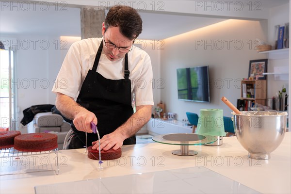 A man baker bakes a red velvet cake at home