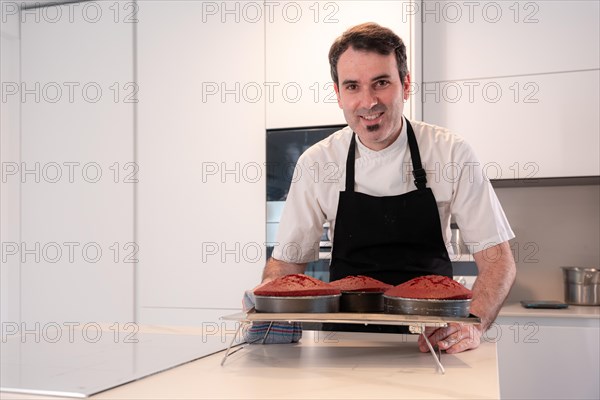 A man baker bakes a red velvet cake at home