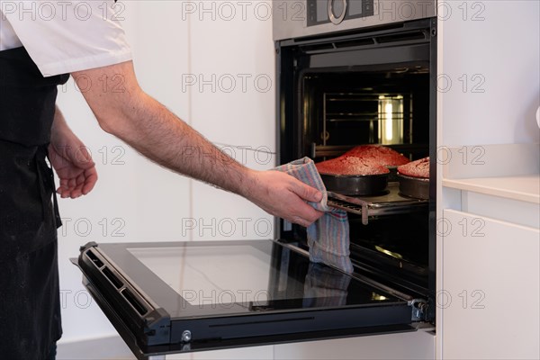 A man baker bakes a red velvet cake at home