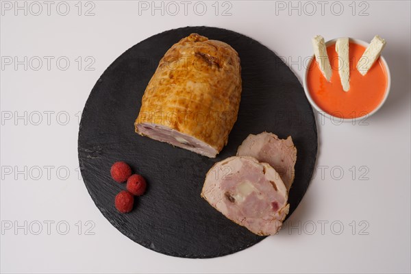 Close-up of a chicken stuffed with raspberry and goat cheese with a bowl of raspberry sauce isolated on white background