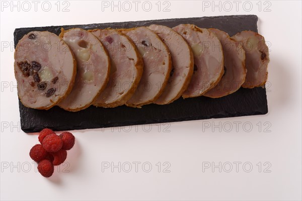 Close-up of a chicken stuffed with raspberry and goat cheese with a bowl of raspberry sauce isolated on white background