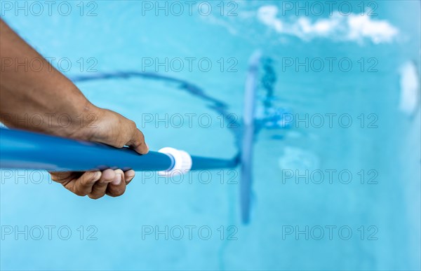 People cleaning swimming pool with suction hose