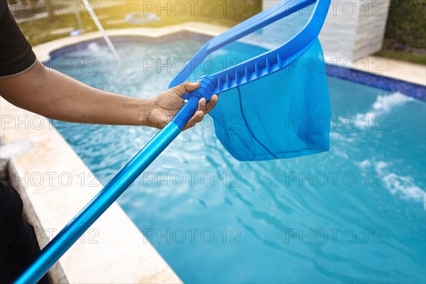 Person with skimmer cleaning pool