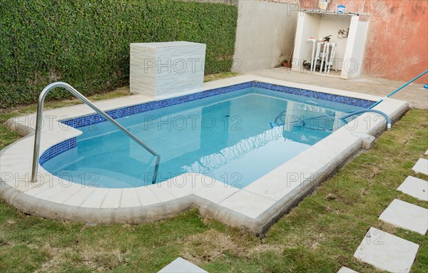 A blue swimming pool with a sand suction hose