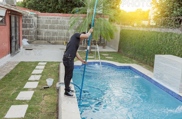 Man cleaning and maintaining swimming pools with a suction hose