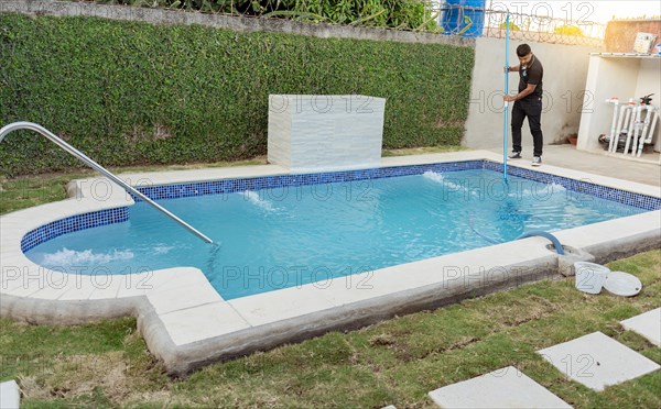 Maintenance person cleaning pool with vacuum hose