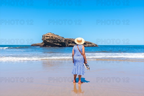 An elderly woman on vacation looking at the sea on the beach in Biarritz