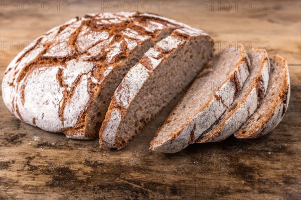 Round rye bread with a crispy crust and flour on an old table