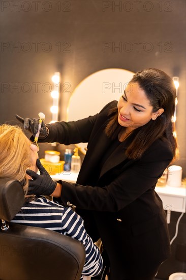 Latin ethnic woman in a beauty shop working with the client's eyebrows
