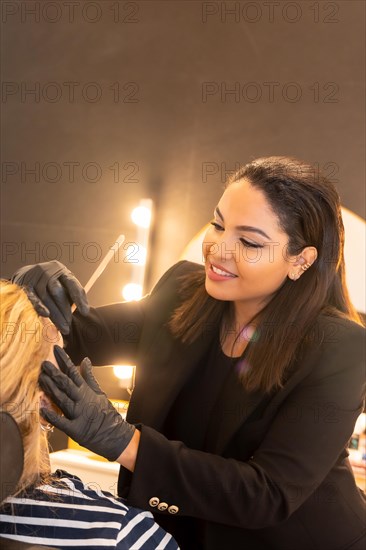 Latina woman in a beauty shop working with the client's eyebrows