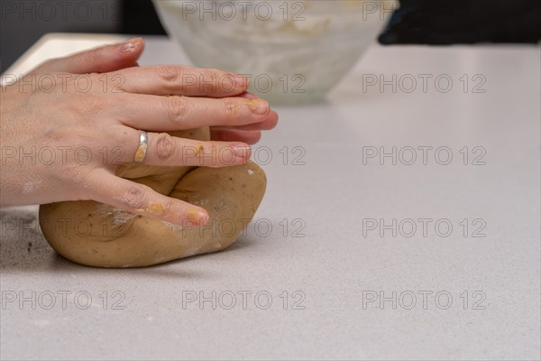 Close-up of womans hands kneading fresh dough for making cookies in her kitchen