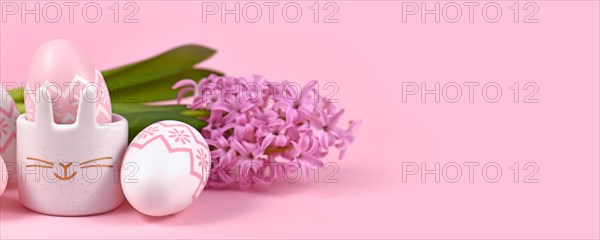 Pink Easter banner with eggs and egg cup in shape of bunny with Hyacinth spring flower on pink background