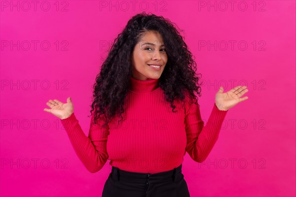 Smiling curly-haired woman posing on a pink background