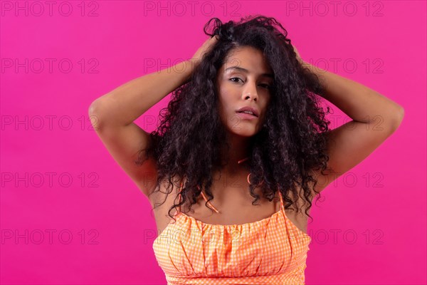 Portrait of a curly-haired woman in summer clothes on a pink background