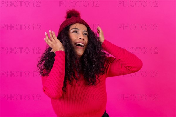 Portrait curly-haired woman in a wool hat on a pink background having fun