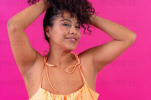 Portrait of a curly-haired woman in summer clothes on a pink background