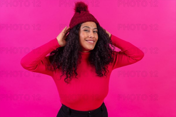 Portrait curly-haired woman in a wool hat on a pink background