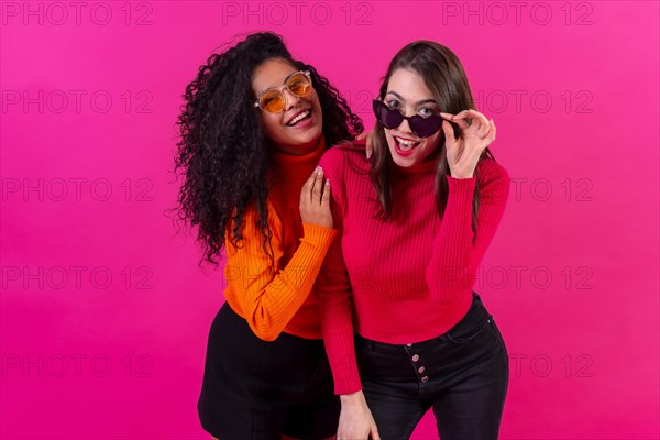 Female friends in sunglasses having fun pink background