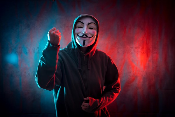 Hacker with anonymous mask with his fist raised in symbol of fight