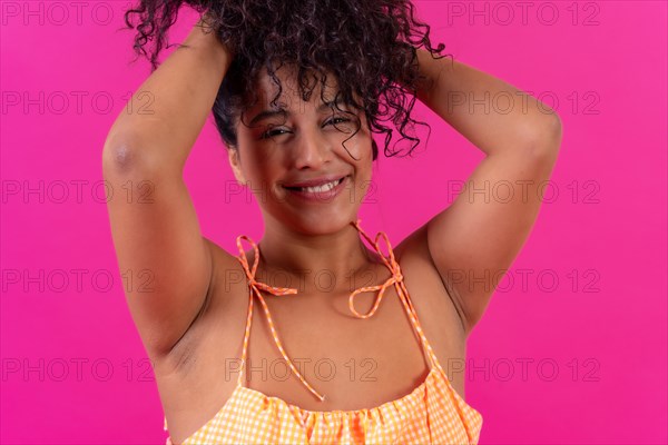 Portrait of a curly-haired woman in summer clothes on a pink background