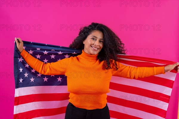Curly-haired woman smiling with usa flag on a pink background