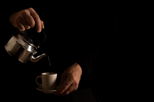 Man's hands serving coffee in dark food shadows