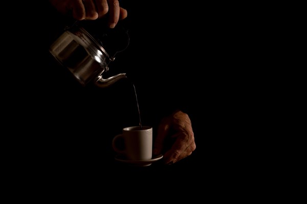 Man's hands serving coffee in dark food shadows