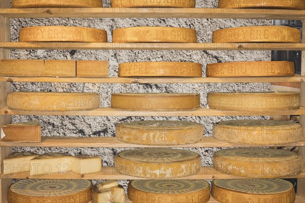 Gruyere cheese wheels stored on a wooden shelf to mature
