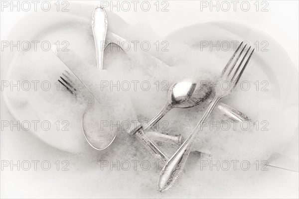 Freshly washed crockery and cutlery in soapy water