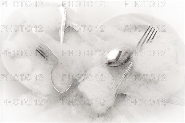 Freshly washed crockery and cutlery in soapy water