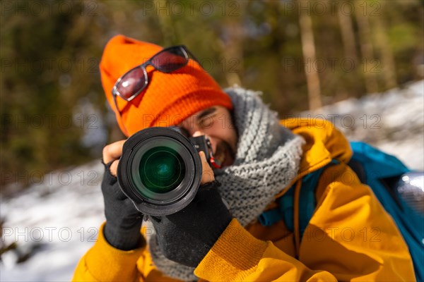 Portrait of a photographer taking winter photos in the mountains with snow doing a trekking with a backpack